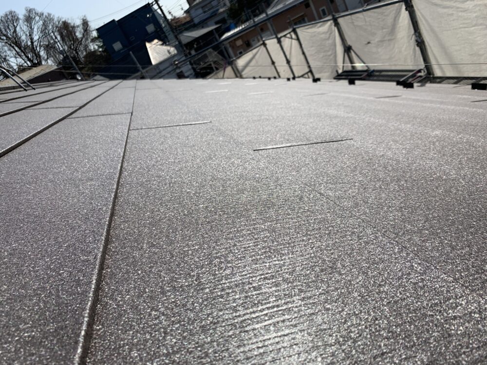 足場越しに見える完成した屋根全景・シェイドブラウン